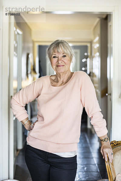 Porträt einer selbstbewussten Seniorin  die zu Hause mit der Hand auf der Hüfte steht.