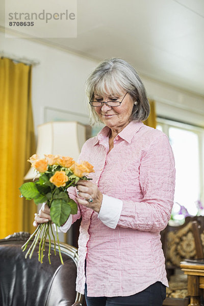 Seniorin mit Blumenstrauß zu Hause
