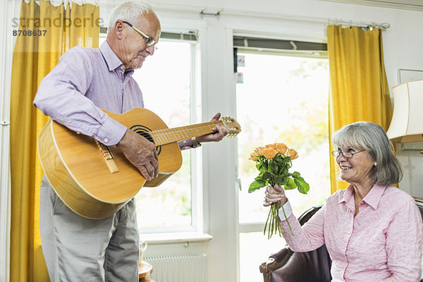 Senior Mann spielt Gitarre für Frau zu Hause