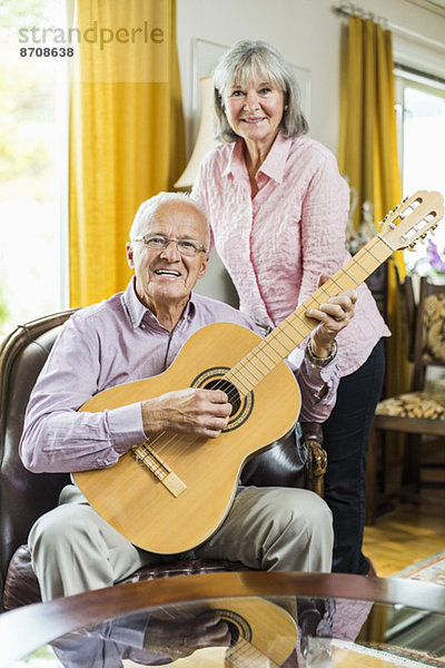 Porträt eines älteren Paares mit Gitarre zu Hause