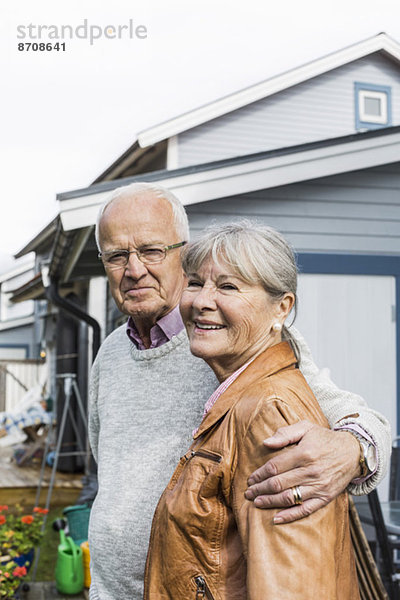 Porträt eines liebenden älteren Paares  das gegen das Haus steht