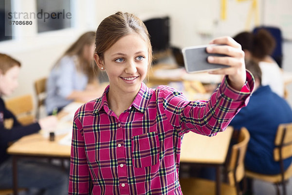 Lächelndes Schulmädchen beim Selbstporträt im Klassenzimmer