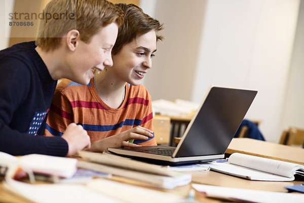Schüler  die den Laptop gemeinsam im Klassenzimmer benutzen
