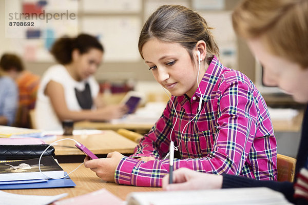 Schülerin beim Musikhören über Smartphone im Klassenzimmer
