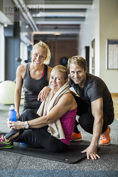 Portrait von glücklichen Instruktoren mit Seniorin im Fitnessstudio