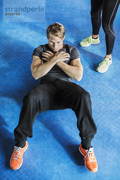 Hochwinkelansicht des Mannes bei Sit-ups im Fitnessstudio