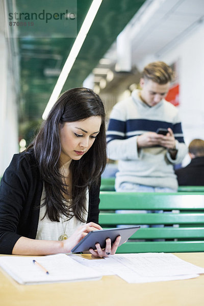 Studentin mit digitalem Tablett und Freund im Hintergrund