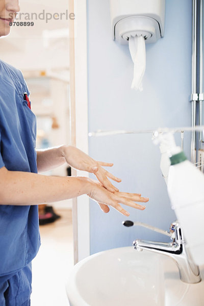 Seitenansicht der jungen Krankenschwester beim Händewaschen im Krankenhausbad