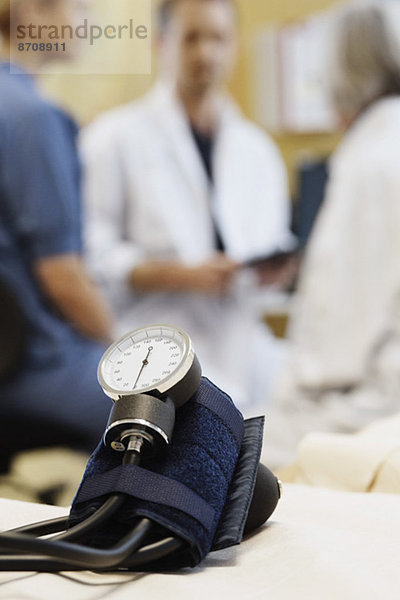 Blutdruckmessgerät mit medizinischem Team diskutiert im Hintergrund