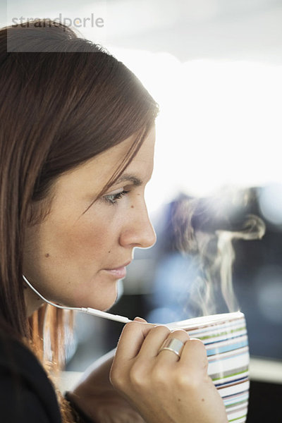 Geschäftsfrau spricht über Kopfhörer beim Kaffee im Büro