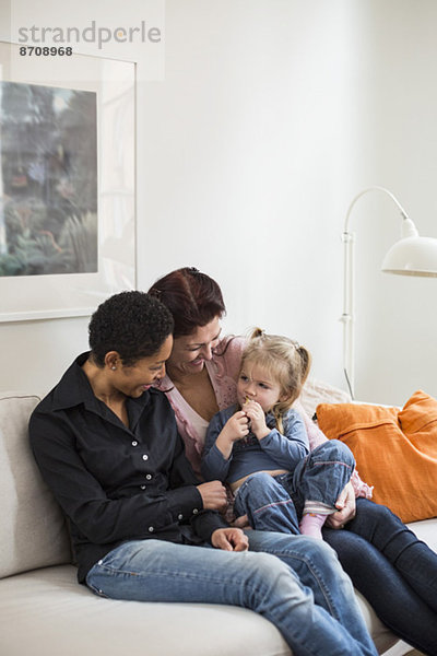 Lesbisches Paar mit Mädchen im Wohnzimmer