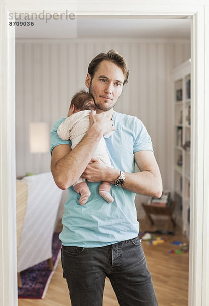 Nachdenklicher Mann mit Baby vor der Tür