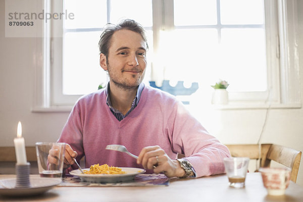 Porträt eines lächelnden Mannes beim Nudelessen