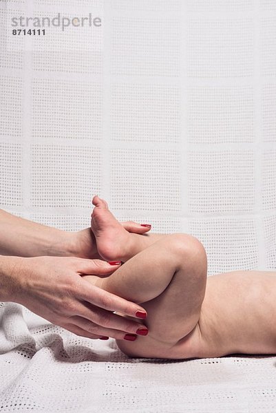 Geschnittene Studioaufnahme von Mütterhänden  die die Füße von Mädchen berühren.