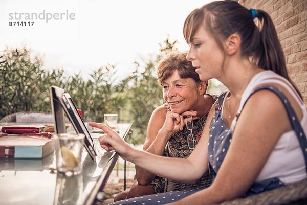 Mutter und mittlere erwachsene Tochter beim Betrachten des digitalen Tabletts