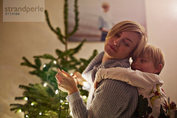 Mutter und Sohn umarmen sich am Weihnachtsbaum