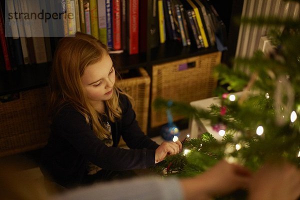 Junges Mädchen schmückt Weihnachtsbaum mit Kugeln