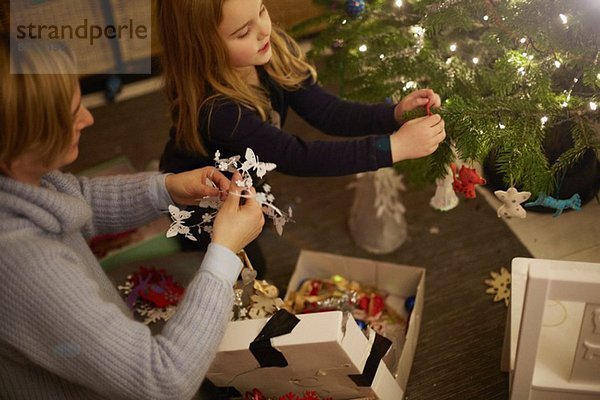 Mutter und Tochter schmücken den Weihnachtsbaum