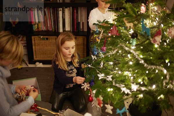 Junge Geschwister schmücken Weihnachtsbaum