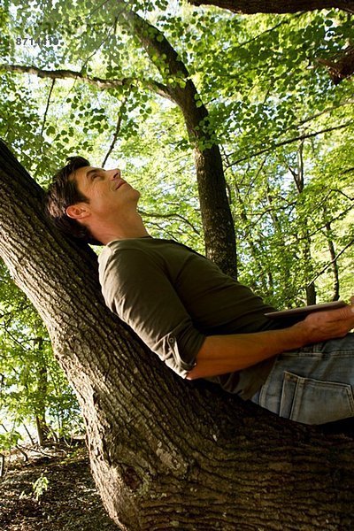 Erwachsener Mann auf Baumstamm im Wald liegend
