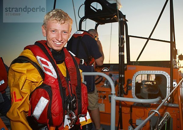 Porträt eines jungen Mannes  der ein Rettungsboot auf See besetzt.