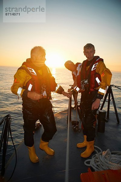 Porträt von drei Männern mit Rettungsbootgeländer auf See