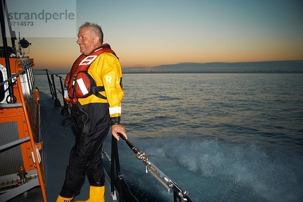 Porträt eines reifen Mannes mit Rettungsbootgeländer auf See
