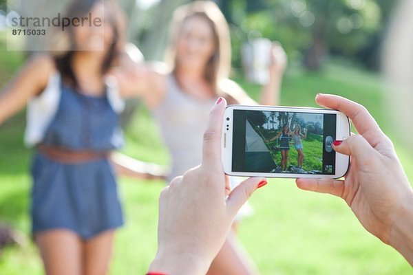 Drei junge Freundinnen beim Fotografieren mit dem Smartphone