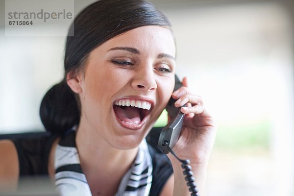 Junge Büroangestellte im Gespräch auf dem Festnetztelefon