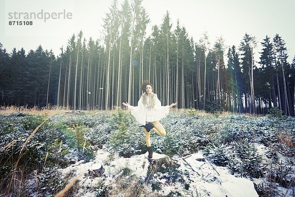 Mittlere erwachsene Frau praktiziert stehende Baum-Yoga-Pose im Wald