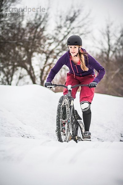 Mittlere erwachsene Mountainbikerin  die sich durch den Schnee kämpft.