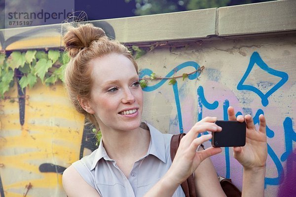 Junge Frau fotografiert auf dem Smartphone