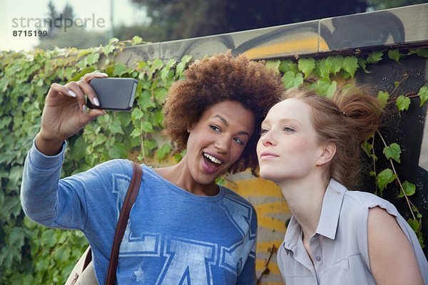 Zwei junge Frauen fotografieren sich selbst auf dem Smartphone