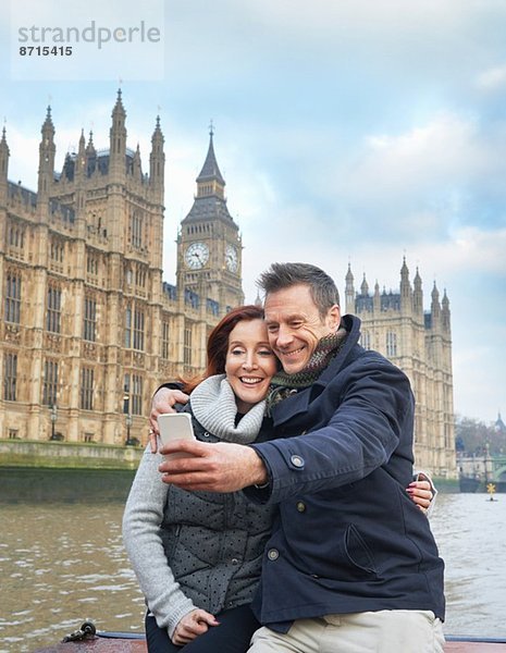 Ein reifes Touristenpaar  das sich selbst und die Häuser des Parlaments fotografiert  London  UK