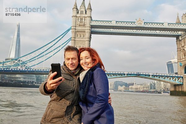 Ein reifes Touristenpaar  das sich selbst und die Tower Bridge fotografiert  London  UK