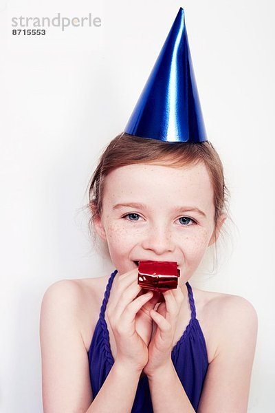Porträt eines Mädchens mit Partybläser mit Partyhut