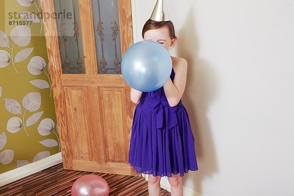 Mädchen beim Aufblasen des blauen Ballons