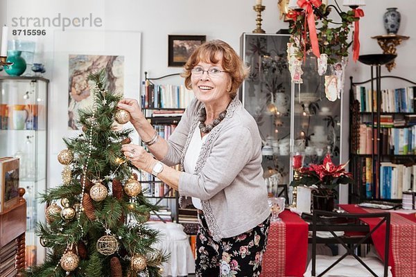 Senior erwachsene Frau schmückt Weihnachtsbaum