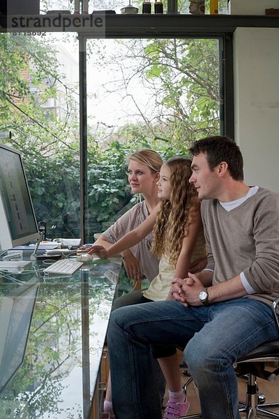 Mädchen und Eltern zu Hause am Computer