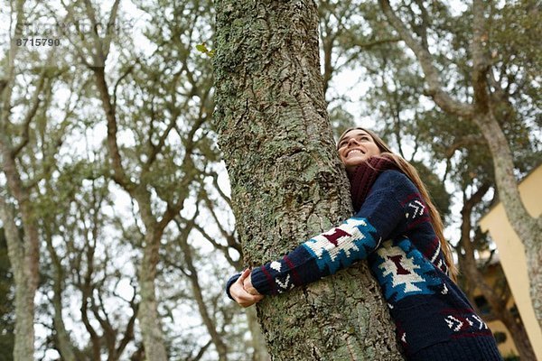 Junge Frau umarmt Baum im Wald