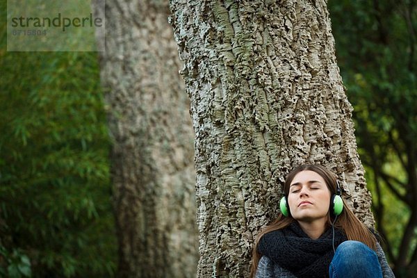 Junge Frau hört Musik im Wald