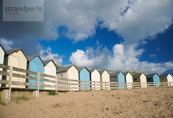 Eine Reihe blauer und weißer Strandhütten  Bude  Cornwall  UK