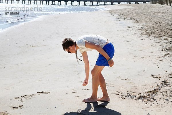 Junger Mann auf der Suche nach Muscheln am Strand  Port Melbourne  Melbourne  Australien