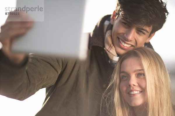 Ein junges Paar fotografiert sich selbst mit Hilfe eines digitalen Tabletts.