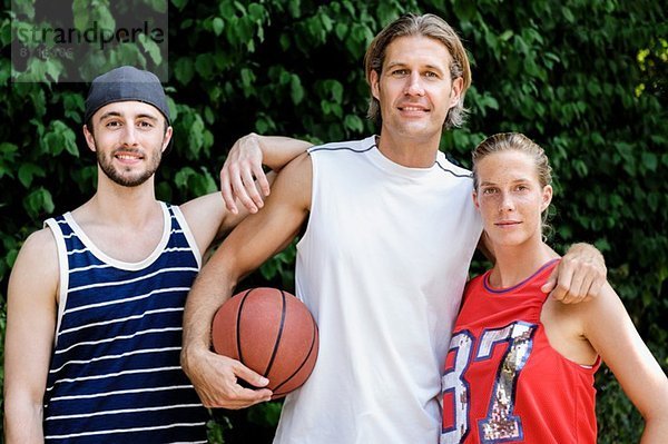 Portrait von drei Basketballspielern im Park