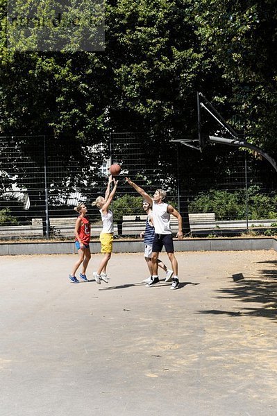 Gruppe von Freunden spielt Basketball auf dem Platz im Park