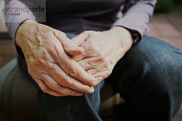 Schnappschuss einer älteren Frau mit Händen auf dem Knie