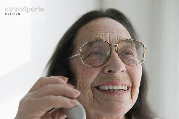 Seniorin mit Brille am Telefon