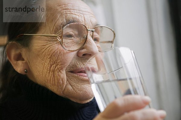 Seniorin mit einem Glas Trinkwasser