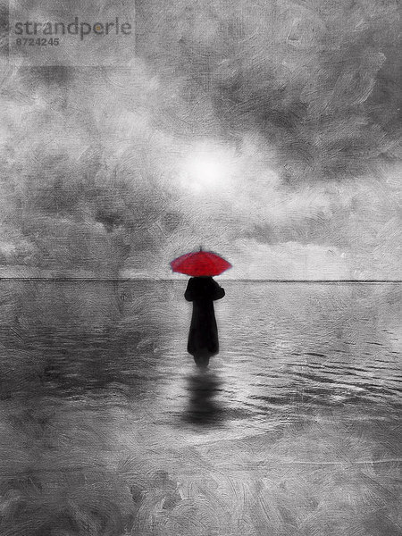 Stimmungsvolle  einsame Frau mit rotem Regenschirm geht ins Wasser